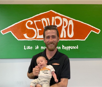 man and baby in front of SERVPRO sign 