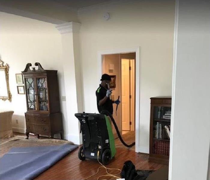 SERVPRO tech using water removal equipment in flooded home